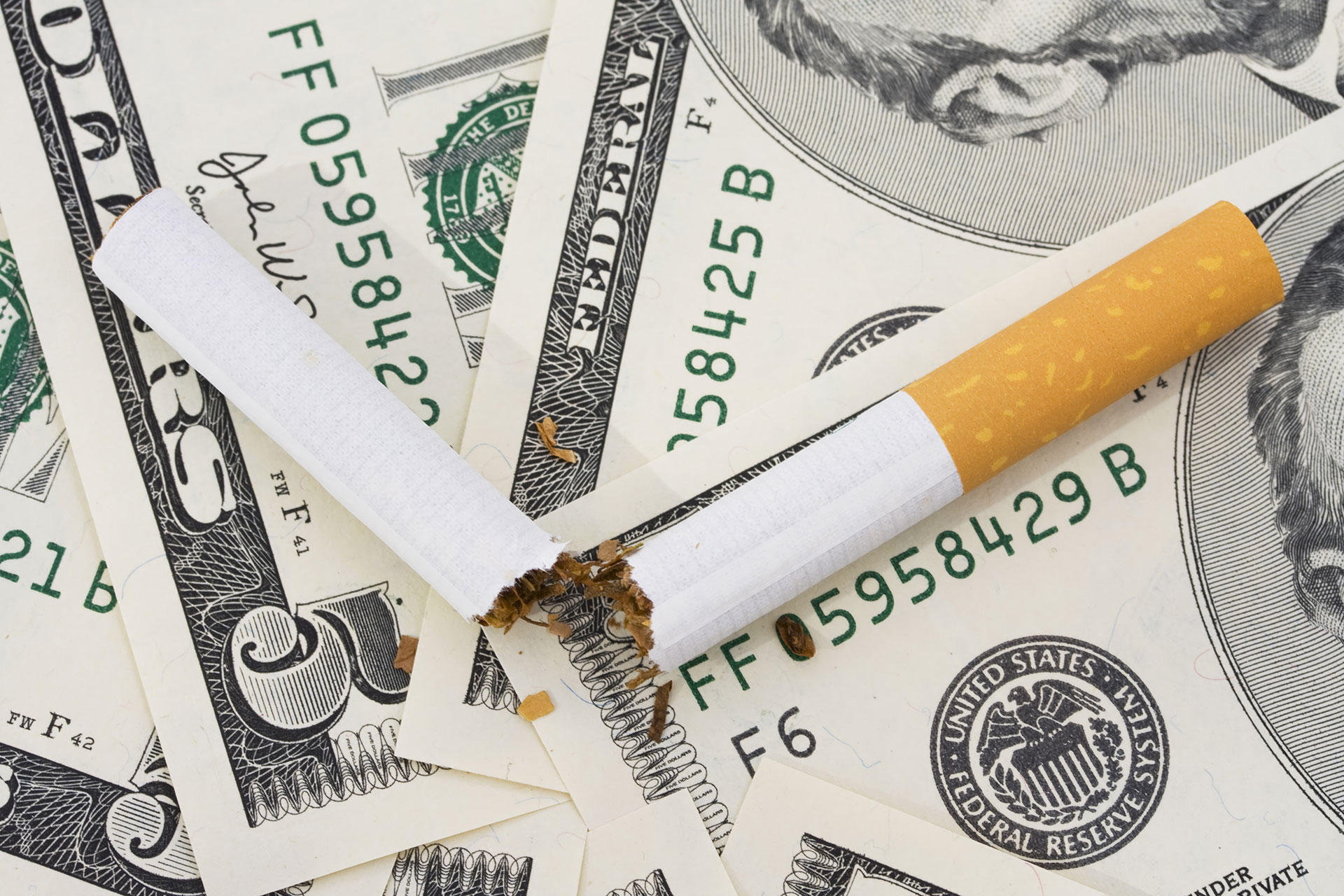 Broken cigarette on American dollar bills