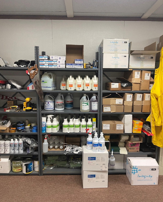 Three metal storage racks full with cleaning supplies organized by type.